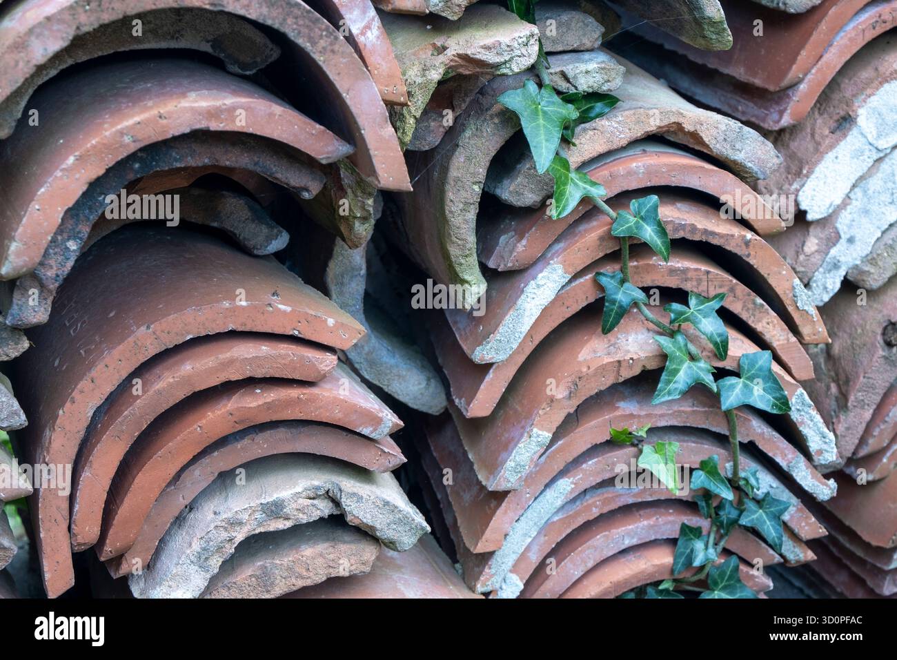 Pile de vieilles tuiles de toit en terre cuite courbées (coppo ou tegola) empilées à l'extérieur, montrant l'usure et la texture naturelle. Banque D'Images