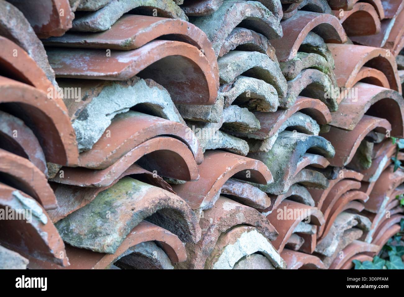 Pile de vieilles tuiles de toit en terre cuite courbées (coppo ou tegola) empilées à l'extérieur, montrant l'usure et la texture naturelle. Banque D'Images