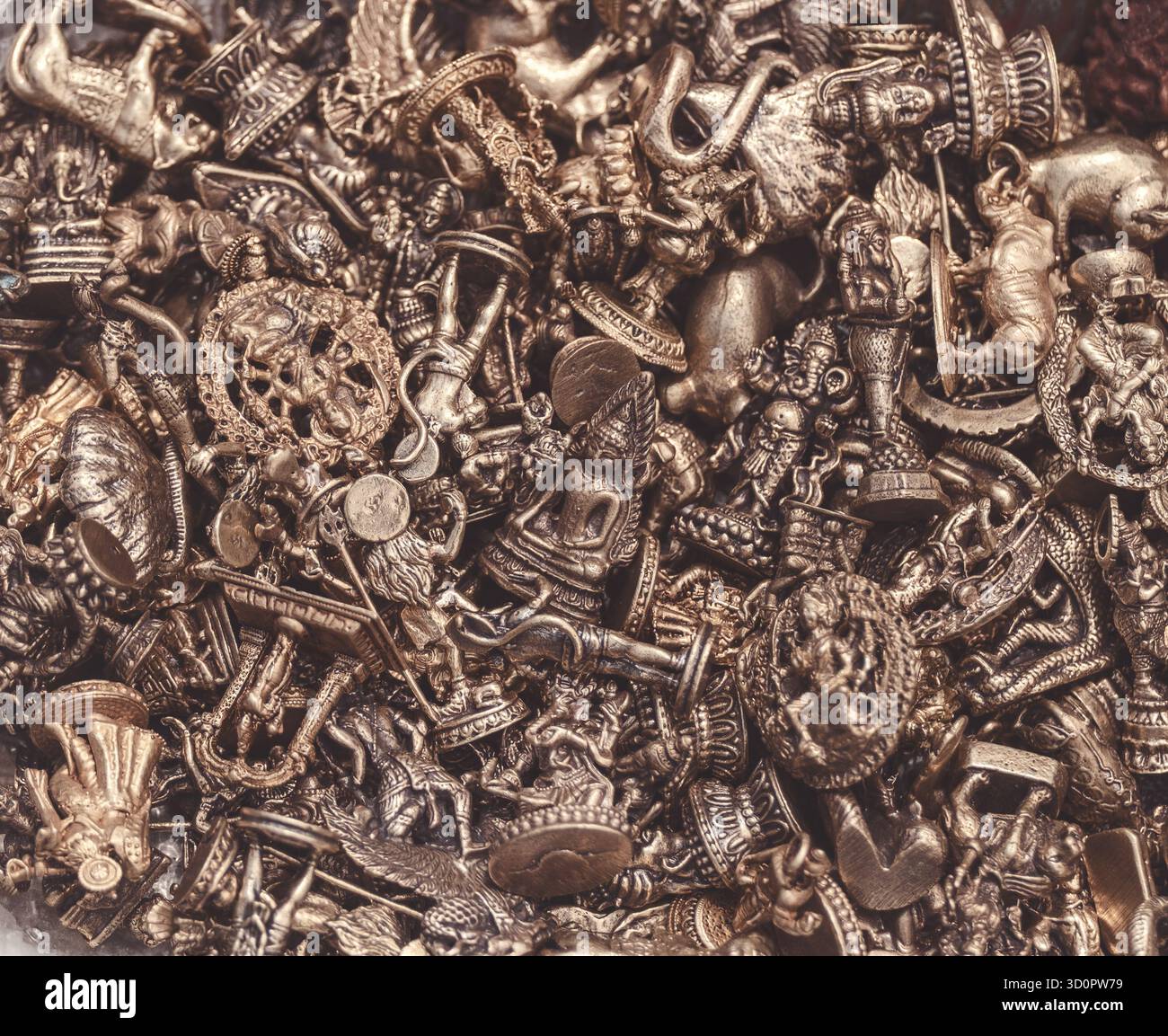 Une collection de petits bibelots en métal vintage, de breloques et de figurines en laiton ou en étain, présentant des formes animales, des divinités religieuses et des décorations Banque D'Images