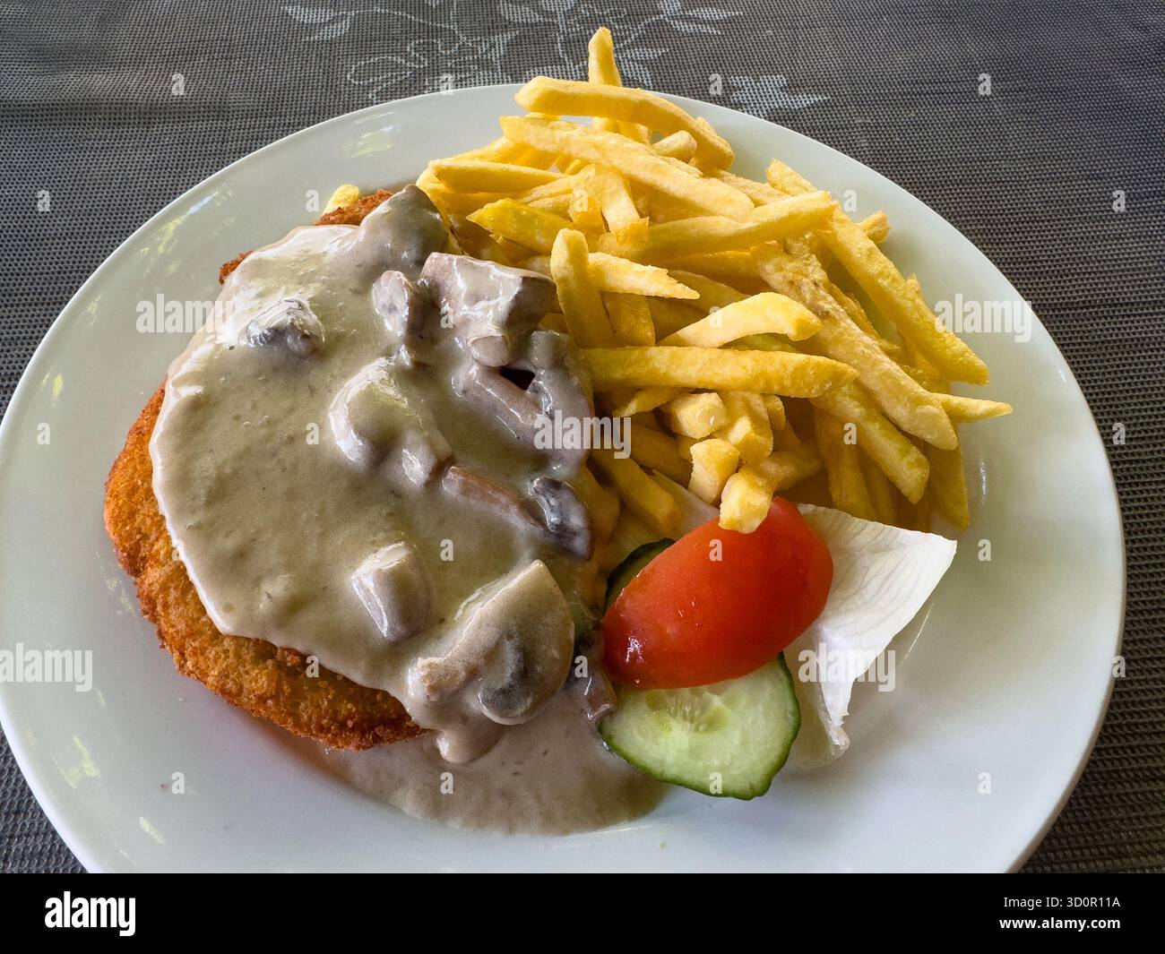 Schnitzel de porc avec une sauce aux champignons et des frites Banque D'Images