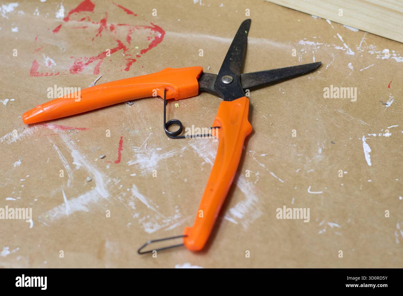 Gros plan de cisailles à élaguer à poignée orange reposant sur un papier brun, capturant les détails de l'outil de jardinage et de sa surface environnante. Banque D'Images