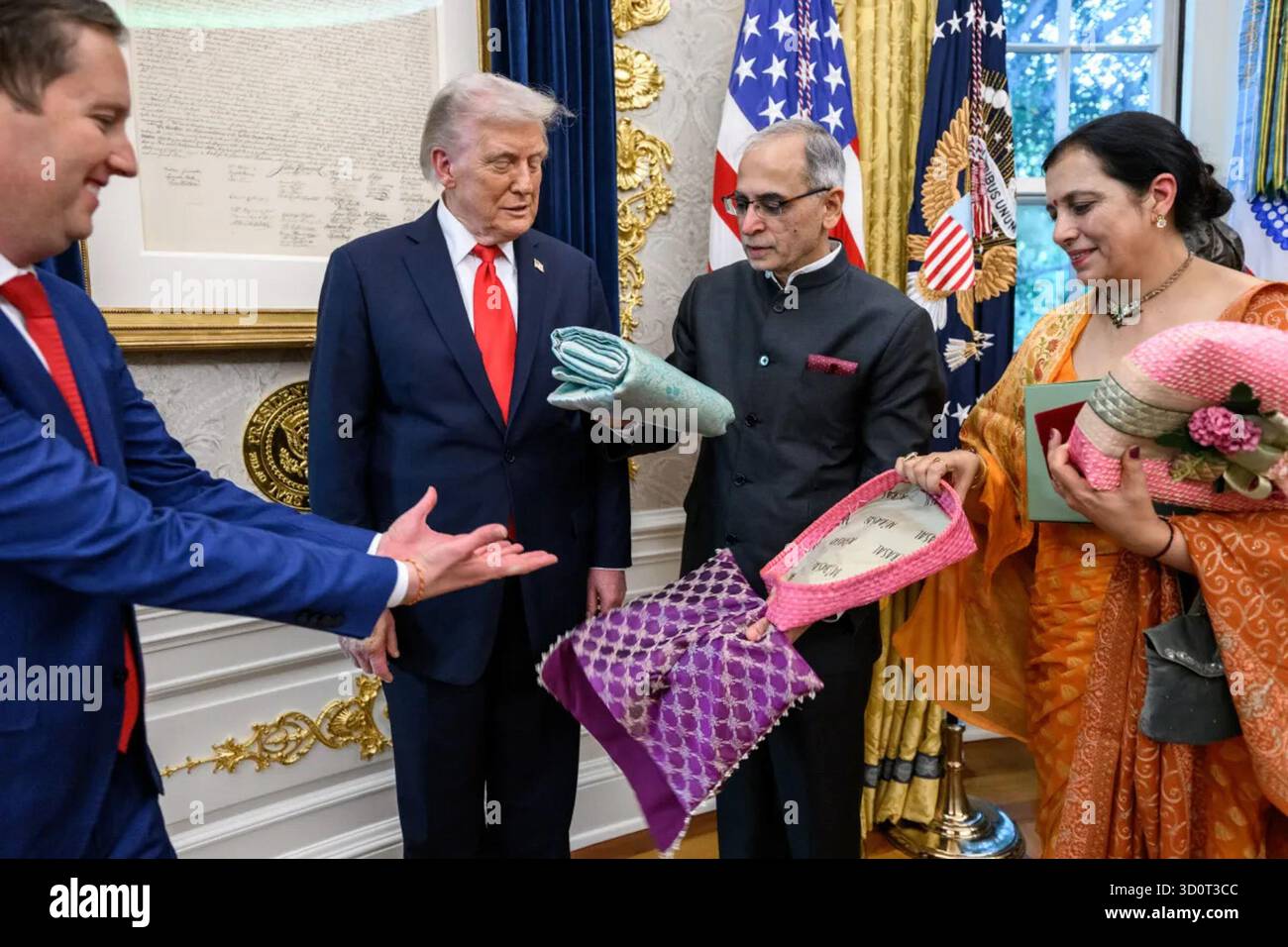 Le président Donald J. Trump reçoit des cadeaux traditionnels indiens de l’ambassadeur Vijay Kwatra et de son épouse lors de la célébration du Diwali dans le bureau ovale de la Maison Blanche, Washington, DC, le 21 octobre 2025. L’échange symbolisait l’amitié et le respect culturel pendant la Fête hindoue des lumières. Image reproduite avec l'aimable autorisation de la Maison Blanche. Banque D'Images