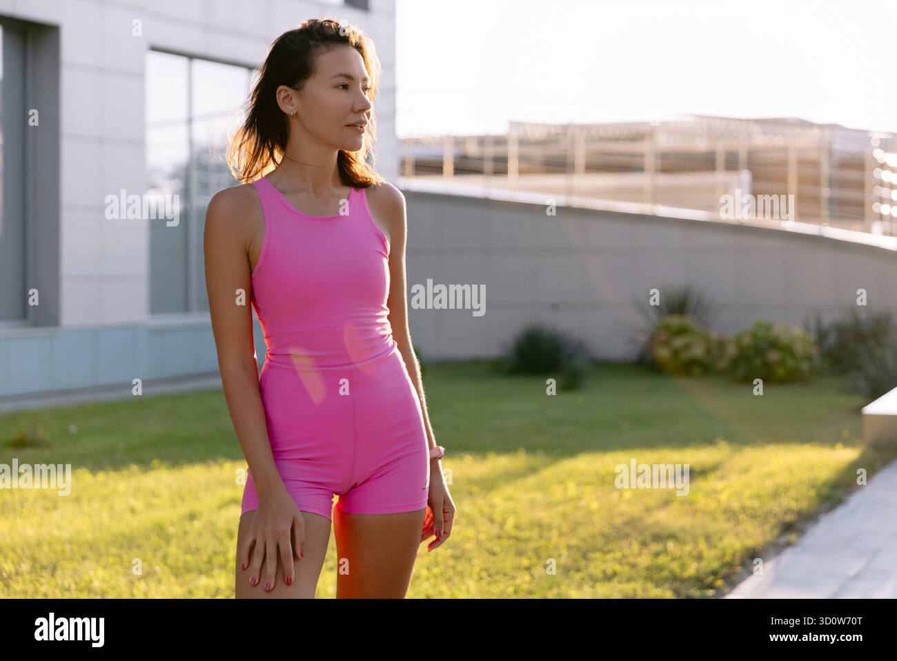 Portrait d'une jeune femme en tenue rose profitant d'une activité de plein air au coucher du soleil dans le parc. Banque D'Images
