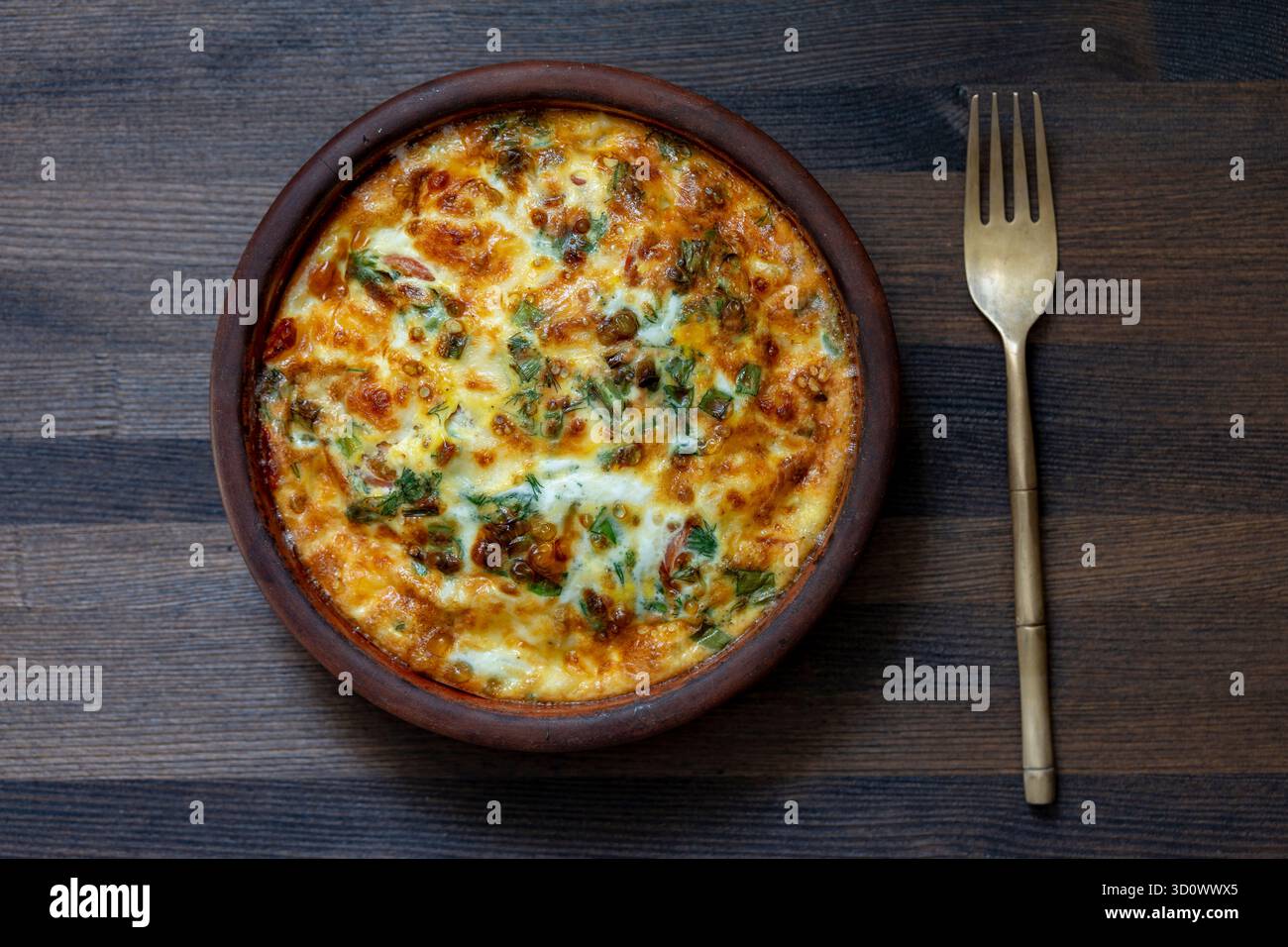 Bol en céramique avec frittata de légumes, nourriture simple. Frittata avec oeufs, poivre, oignon, légumes verts et fromage sur table en bois, gros plan, vue de dessus. Italien e Banque D'Images