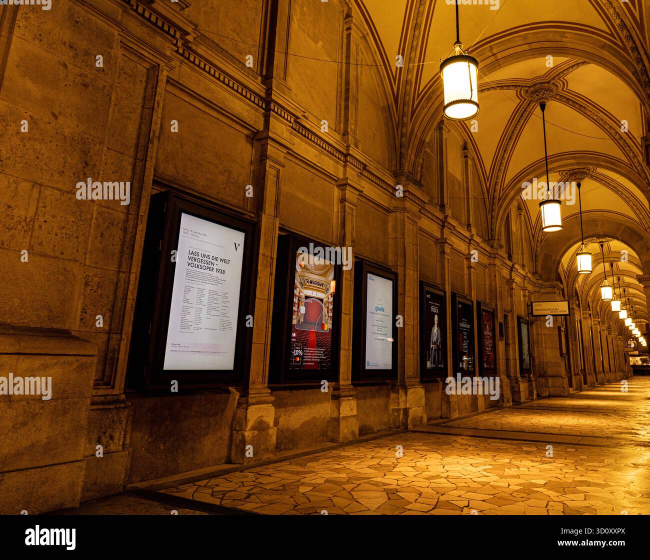 Vue en perspective du couloir extérieur de l'Opéra national de Vienne (Wiener Staatsoper) avec lumières allumées et publicités Banque D'Images