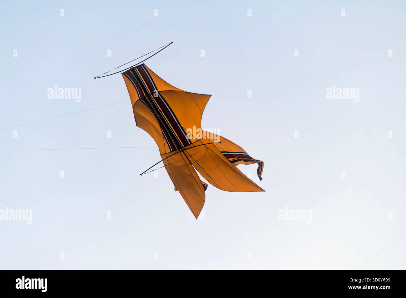 Un cerf-volant traditionnel Bebean jaune vif flotte dans le ciel, en forme de poisson avec une large étendue et une longue queue. Banque D'Images