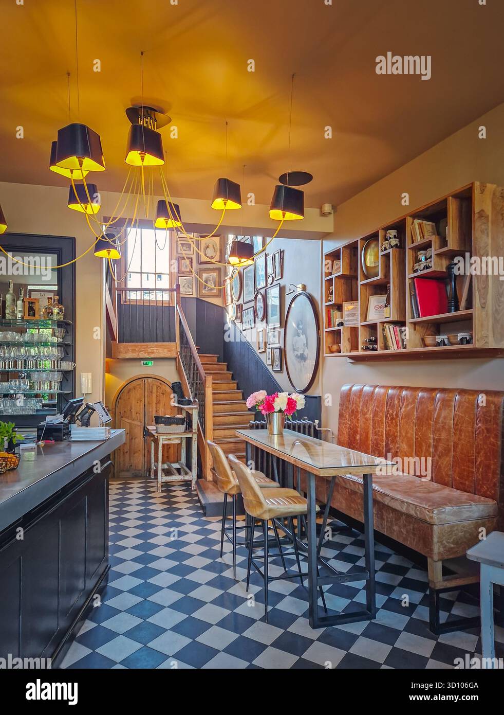 Intérieur chaleureux et éclectique d'un bar du hall avec un sol en damier saisissant et un groupe de suspensions modernes au plafond. Ambiance chaleureuse et vivante Banque D'Images