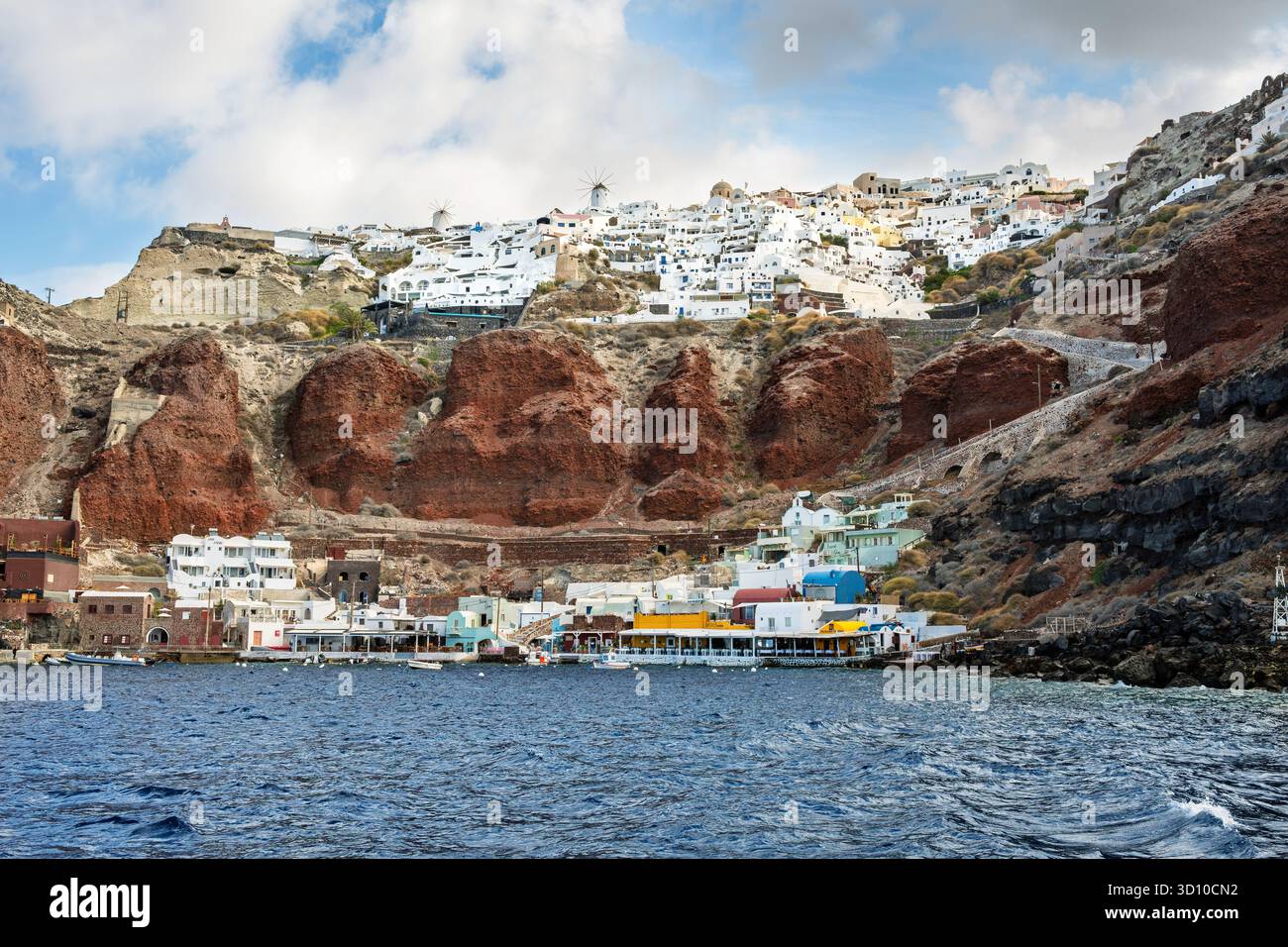 Amoudi Bay, un petit port situé sous les falaises volcaniques rouges frappantes et le village blanchi à la chaux d'Oia sur l'île grecque de Santorin, en Grèce. Banque D'Images