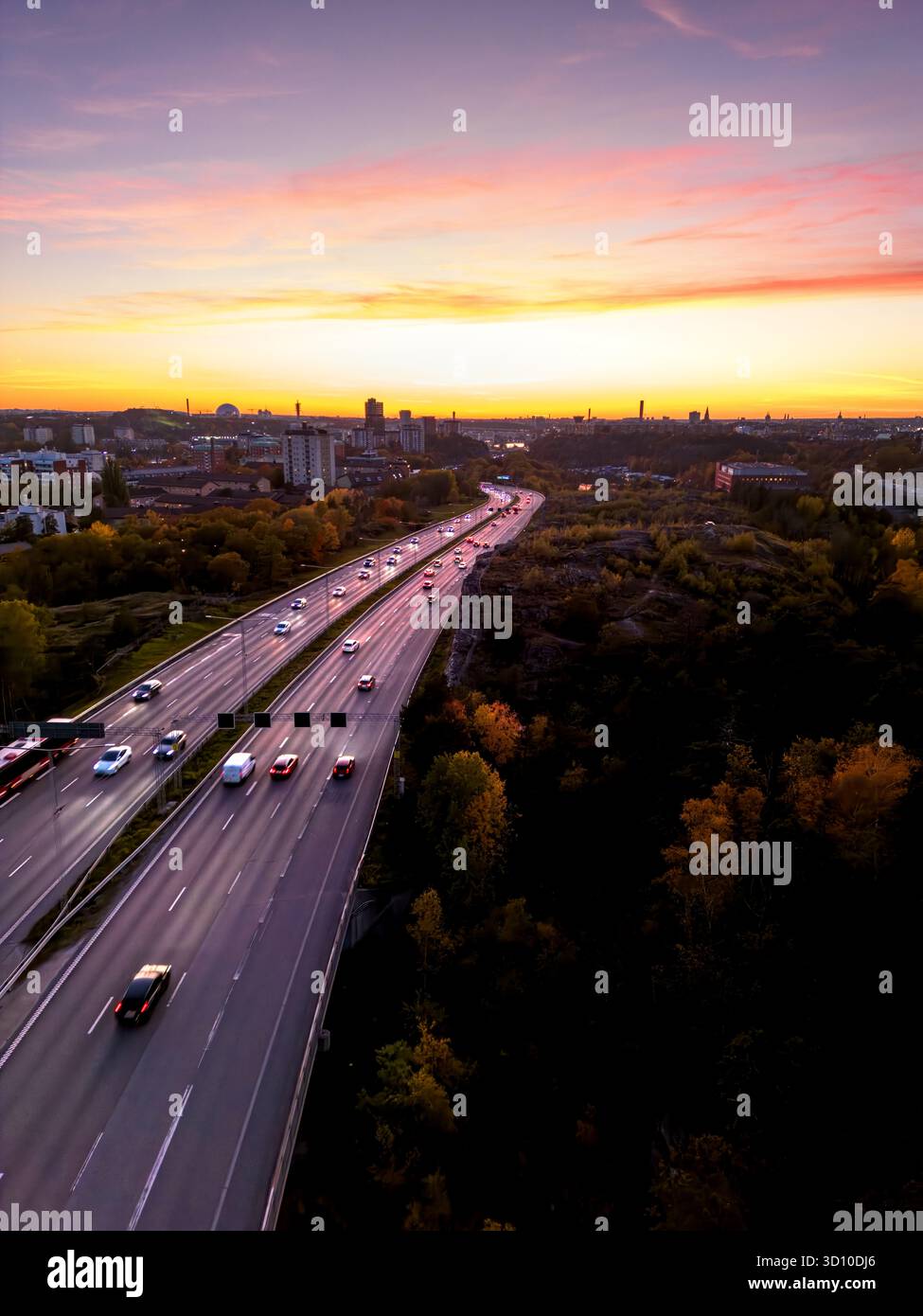 Vue aérienne de l'autoroute avec six voies menant à un paysage urbain avec le ciel coloré du coucher du soleil Banque D'Images