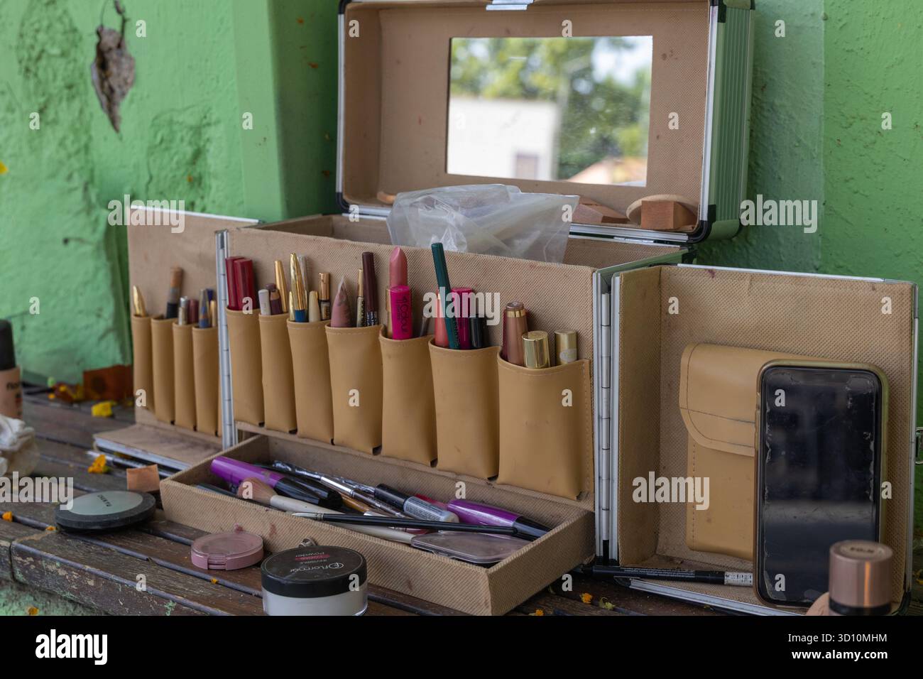 Kit de maquillage professionnel ouvrant, révélant divers cosmétiques et outils prêts pour une routine beauté sur une table en bois rustique Banque D'Images