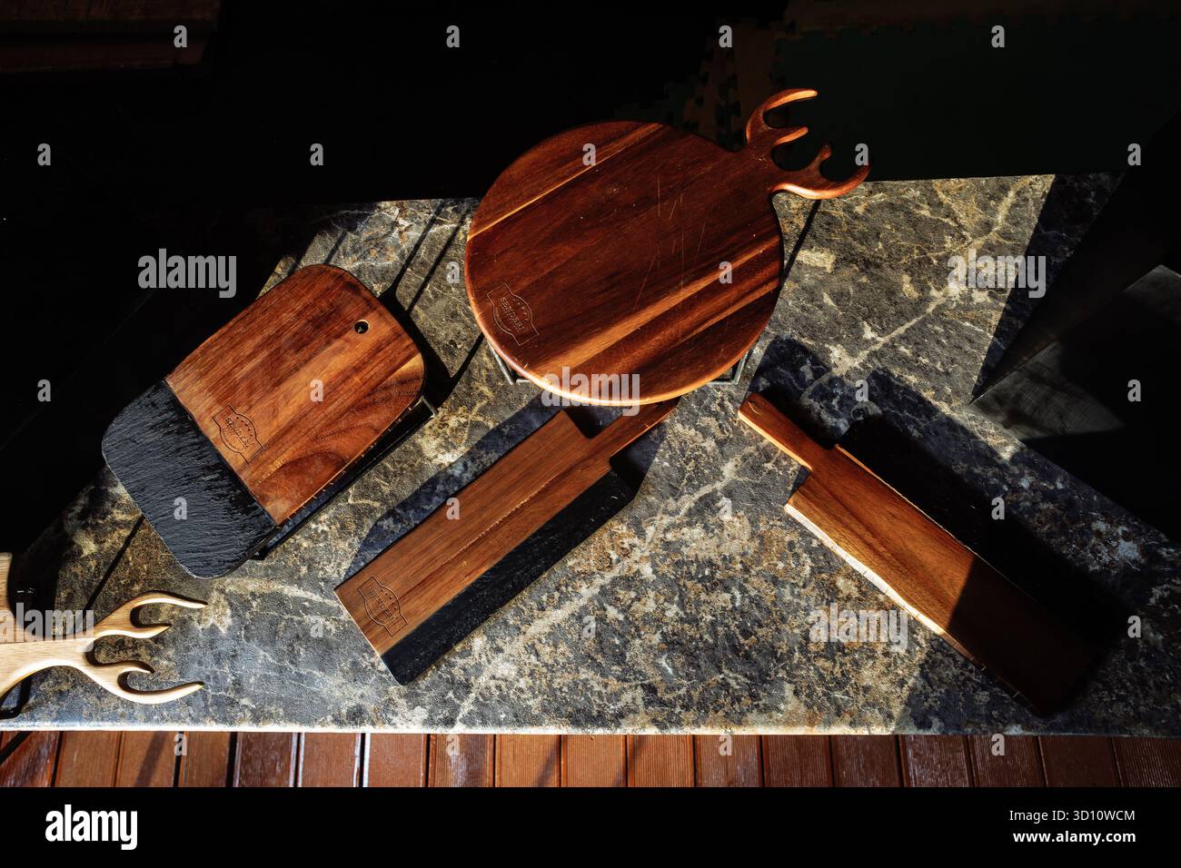 Planches de service artisanales en bois et en ardoise disposées dans une lumière dramatique - parfaites pour les marques d'ustensiles de cuisine ou la narration de décoration de luxe. Banque D'Images