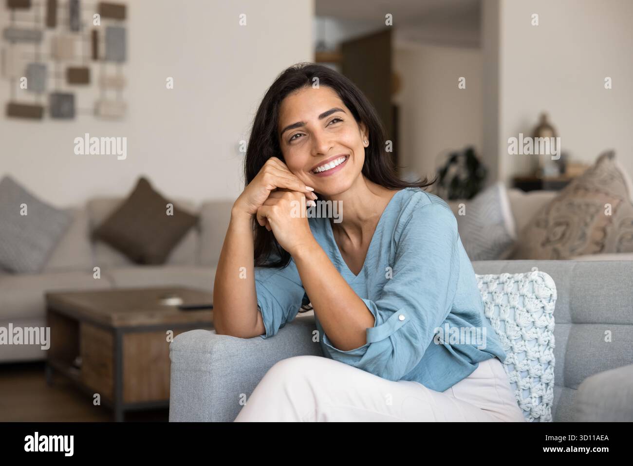 Joyeuse belle jeune femme hispanique assise sur un canapé confortable Banque D'Images