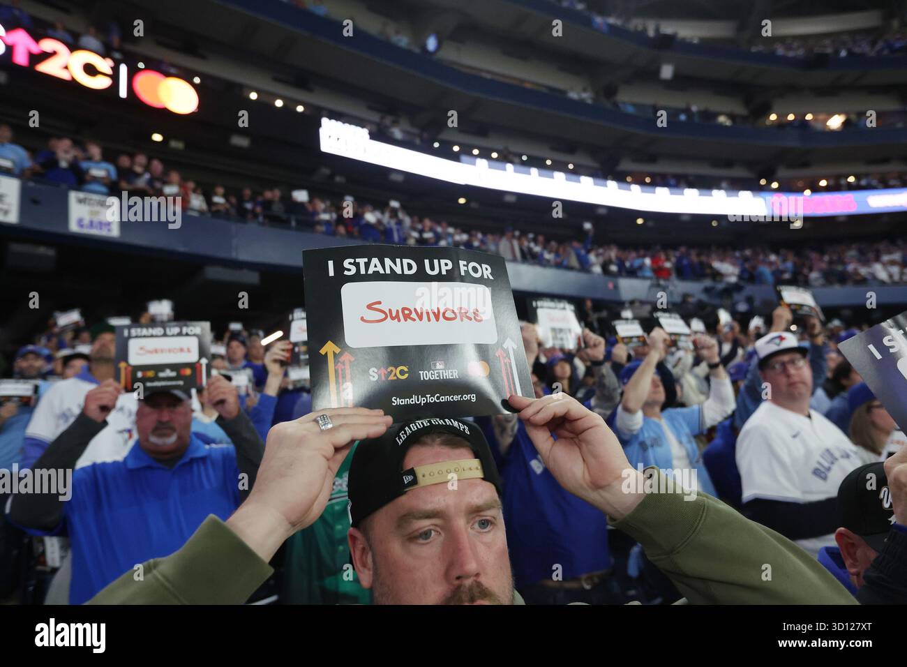 Toronto, Canada. 25 octobre 2025. Les amateurs de baseball détiennent des cartes montrant leur soutien à la recherche sur le cancer lors du deuxième match de la série mondiale MLB entre les Dodgers de Los Angeles et les Blue Jays de Toronto au Rogers Centre à Toronto, Canada, le samedi 25 octobre 2025. Photo de Aaron Josefczyk/UPI crédit : UPI/Alamy Live News Banque D'Images