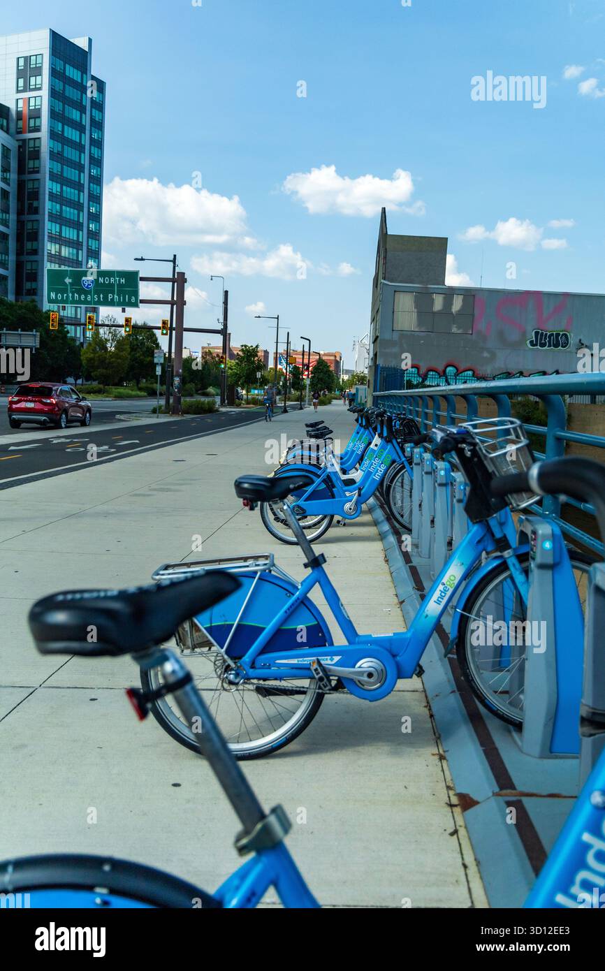 Une rangée de vélos bleus est garée sur un trottoir à côté d'un bâtiment. Les vélos sont enchaînés à une rampe métallique. Course St Pier, Philadelphie Banque D'Images Une rangée de vélos bleus est garée sur un trottoir à côté d'un bâtiment. Les vélos sont enchaînés à une rampe métallique. Course St Pier, Philadelphie Banque D'Images