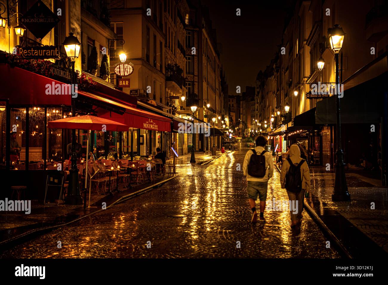 Vue nocturne des restaurants et cafés de la rue Montorgueil avec réflexions après la pluie – Paris, France Banque D'Images