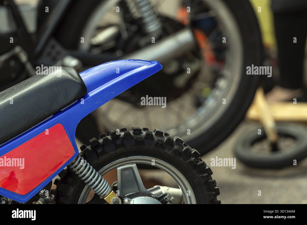 Moto bleu vif présentée à côté d'une moto plus grande dans un cadre d'atelier Banque D'Images
