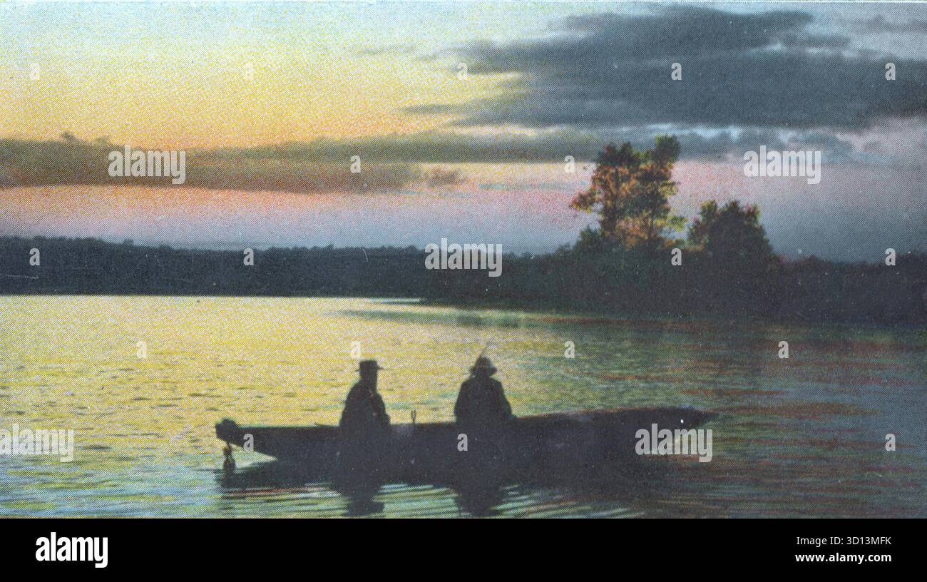 Deux personnages sont assis tranquillement dans une barque alors que le crépuscule s'installe sur un lac calme. Le ciel brille avec une lumière qui s'estompe — orange, jaune et bleu — tandis que les nuages sombres dérivent au-dessus. Les arbres bordent le rivage lointain en silhouette. Intitulée Evening Shadows, cette carte postale 1908 de Russell Brothers capture un moment de calme, de réflexion et de beauté naturelle. D'une carte postale originale. Banque D'Images
