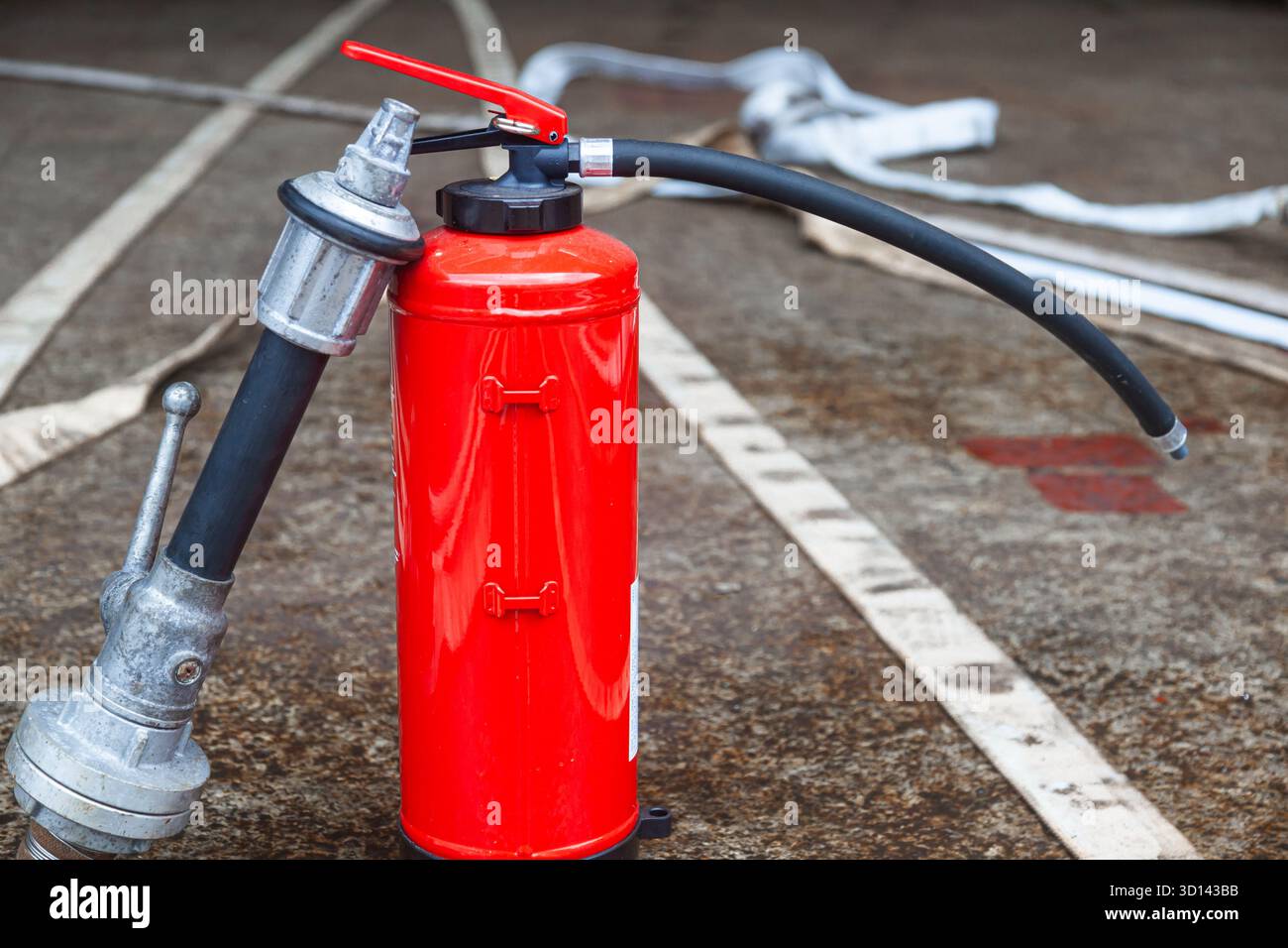Cylindre d'extincteur rouge avec tuyaux d'incendie déroulés. Banque D'Images