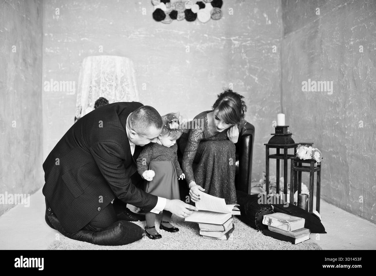 Famille heureuse avec sa fille lire le livre ancien sur fond tapis décor vintage prix avec Banque D'Images