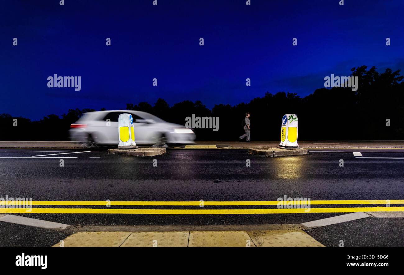 une voiture accélérant psat un passage à niveau pendant qu'un piéton marche sur le trottoir Banque D'Images