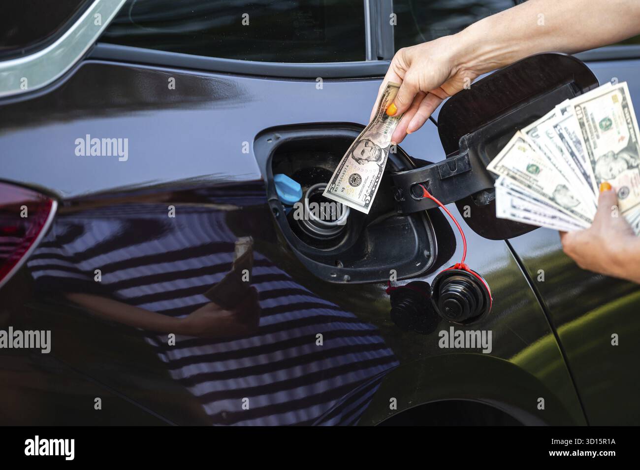 Main de femme qui met de l'argent dans le réservoir de voiture, gros plan, concept de carburant cher, crise de carburant Banque D'Images