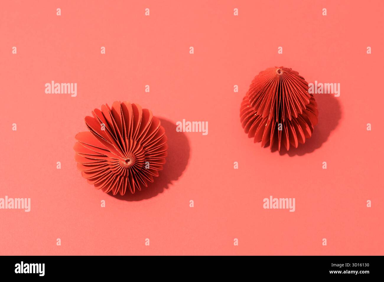 Boules d'arbre de Noël en papier rouge à la mode, projet DIY, design moderne organique. Boules 3D pliables en nid d'abeilles festives. Composition minimaliste sur dos rouge Banque D'Images