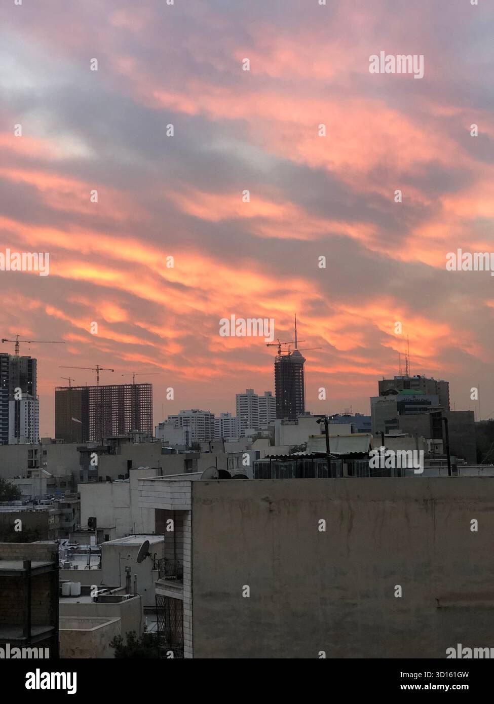 Ciel coloré de coucher de soleil sur la ligne d'horizon de la ville de Téhéran, Iran, avec des bâtiments modernes et des grues. Banque D'Images