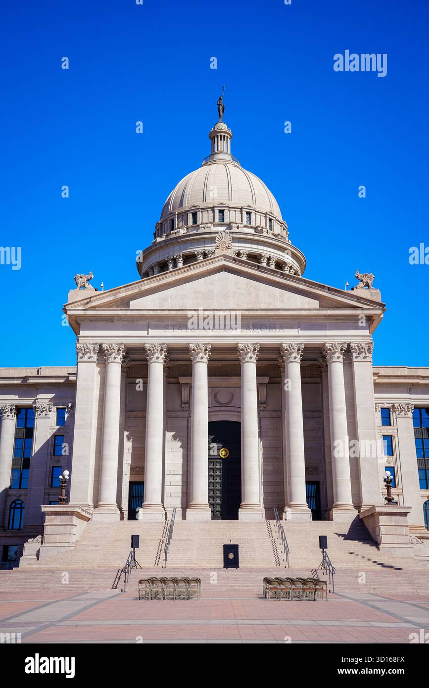 Composition verticale du dôme du Capitole de l'État d'Oklahoma et des colonnes sous un ciel bleu, mettant en évidence la statue du gardien et l'architecture symétrique Banque D'Images