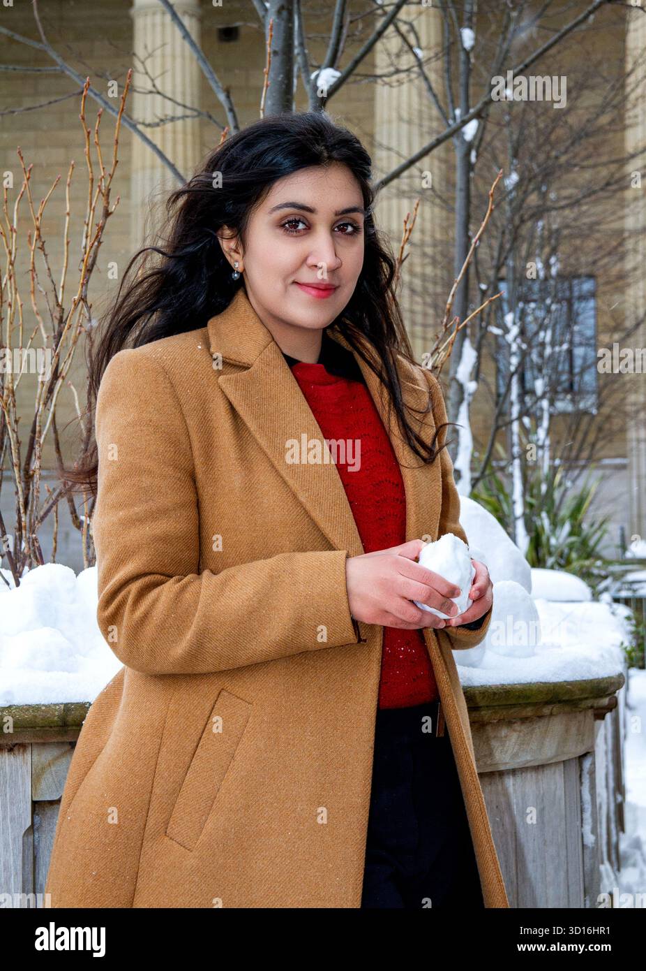 Une femme magnifique aux longs cheveux bruns s'amuse dans la neige un jour d'hiver dans le centre-ville de Dundee, en Écosse Banque D'Images