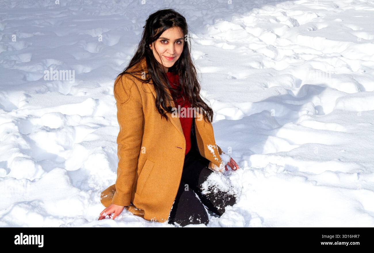 Une femme magnifique aux longs cheveux bruns s'amuse dans la neige un jour d'hiver dans le centre-ville de Dundee, en Écosse Banque D'Images