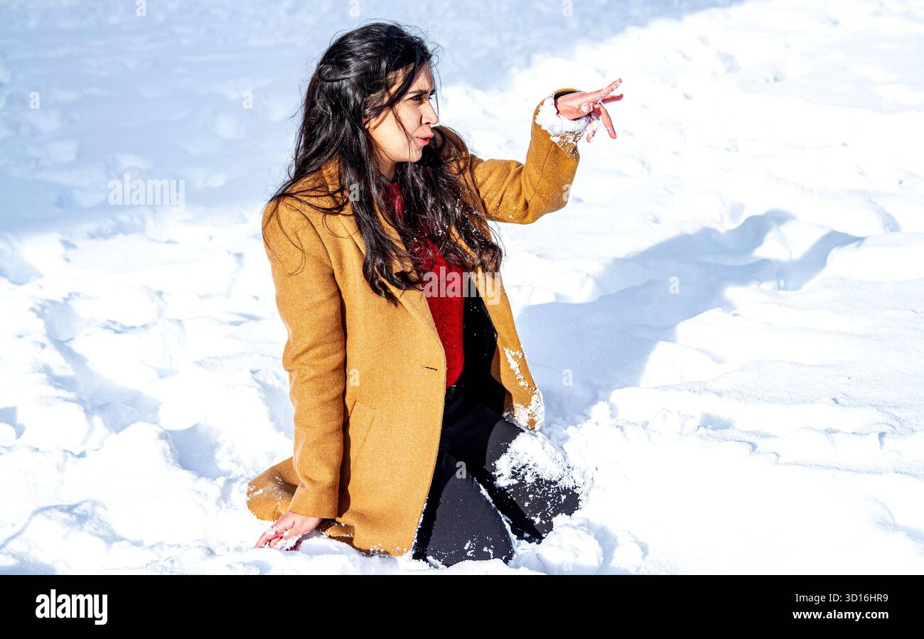 Une femme magnifique aux longs cheveux bruns s'amuse dans la neige un jour d'hiver dans le centre-ville de Dundee, en Écosse Banque D'Images