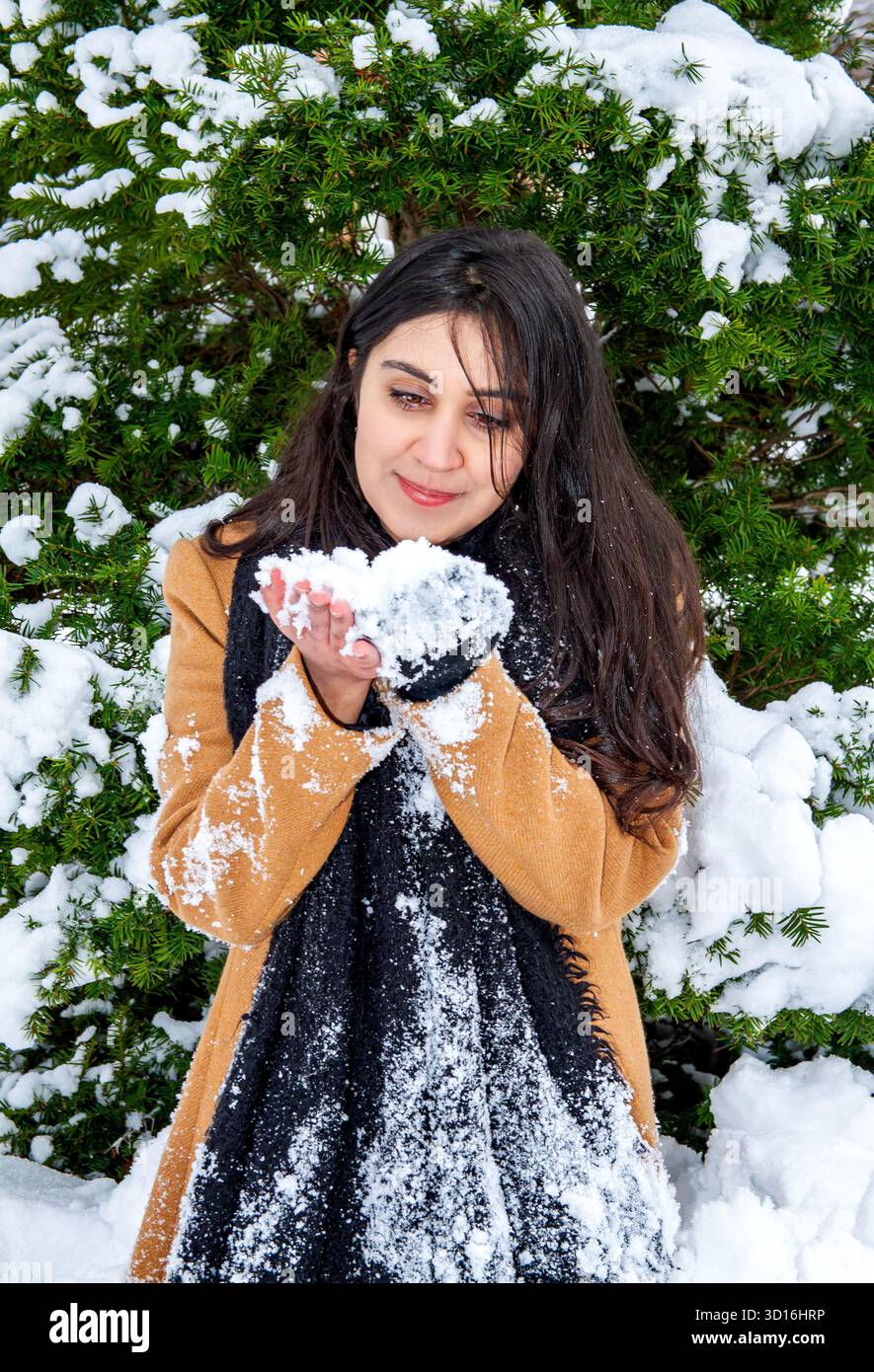 Une femme magnifique aux longs cheveux bruns s'amuse dans la neige un jour d'hiver dans le centre-ville de Dundee, en Écosse Banque D'Images