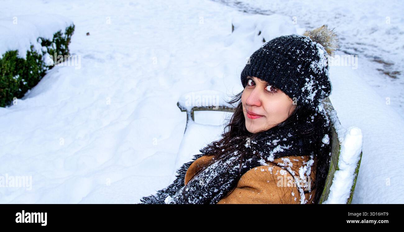 Une femme magnifique aux longs cheveux bruns s'amuse dans la neige un jour d'hiver dans le centre-ville de Dundee, en Écosse Banque D'Images