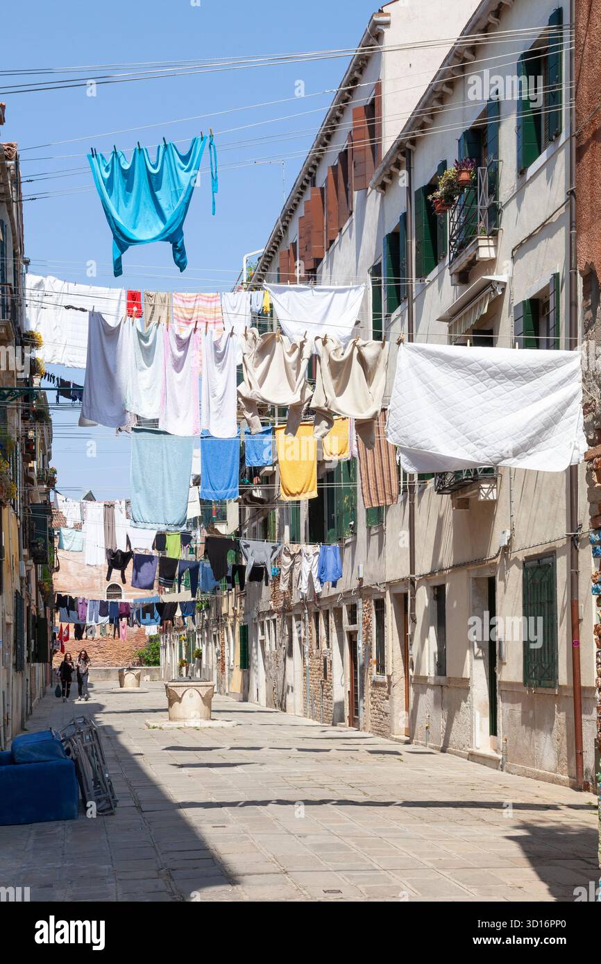 Journée de lavage coordonnée à Venise avec linge suspendu à l'extérieur séchant sur plusieurs lignes de lavage couvrant un campiello, Italie. La vie quotidienne vénitienne Banque D'Images