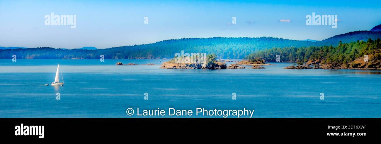 Voilier à voile sur les eaux bleues calmes près des îles forestières Banque D'Images