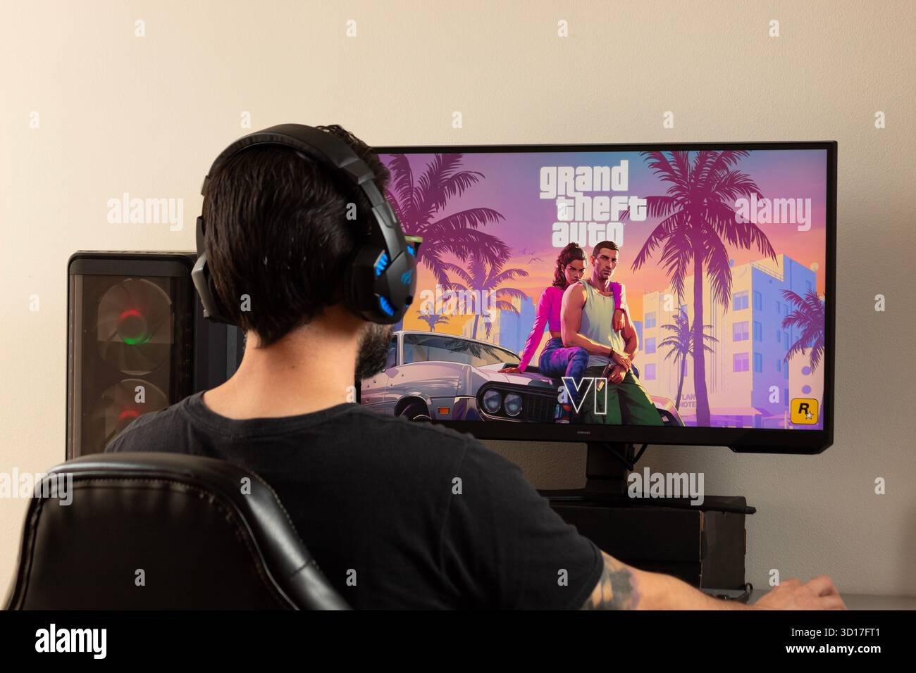 Un joueur d'homme utilisant des écouteurs de joueur jouant grand Theft auto 6 jeu vidéo sur un ordinateur de joueur Banque D'Images