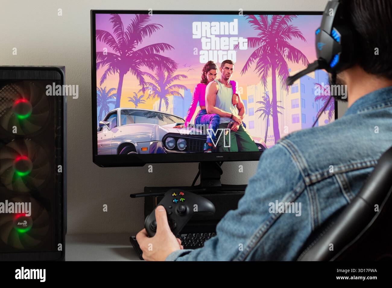 Gros plan sur un joueur masculin sur le côté droit de l'image tenant une manette xbox regardant un moniteur de pc avec grand vol auto 6 jeu vidéo Banque D'Images