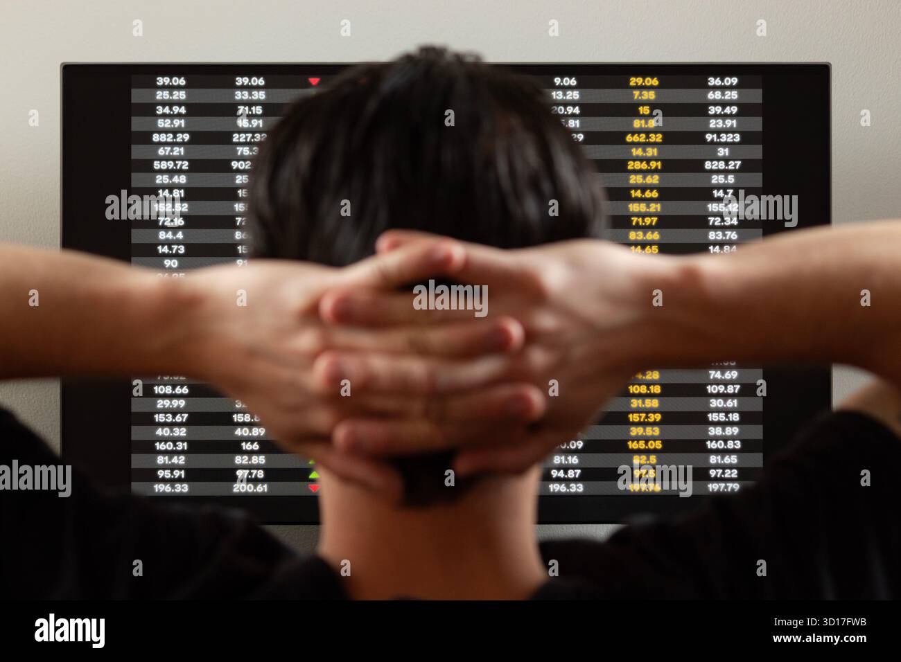 Gros plan sur l'arrière d'un homme dans l'attitude relaxante regardant un écran avec des valeurs boursières Banque D'Images