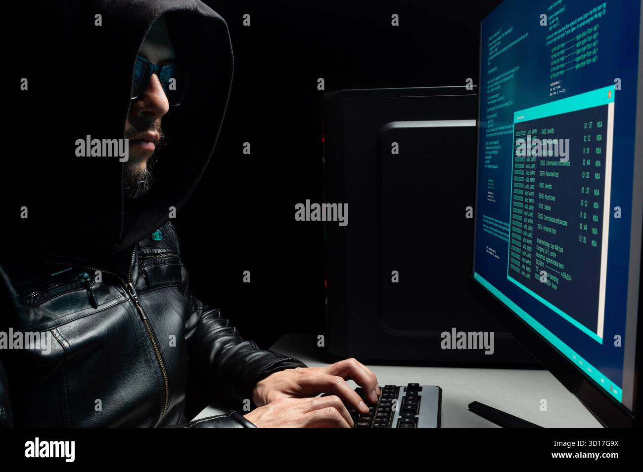 gros plan sur un homme hacker cagoulé écrivant sur un ordinateur à clavier et regardant un logiciel hacker bleu dans une atmosphère criminelle Banque D'Images