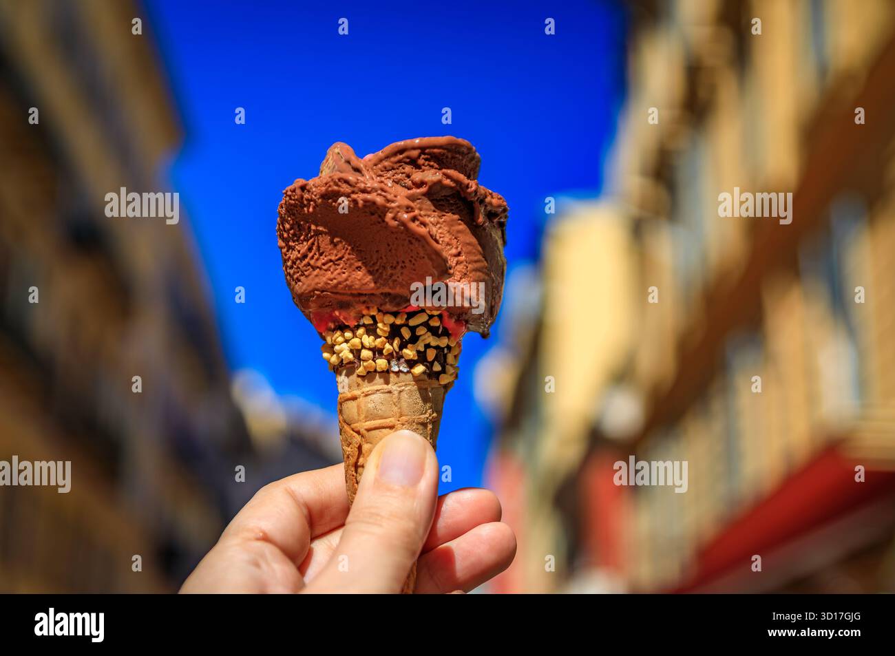 Main tient un cône de gelato au chocolat artisanal, vue sur les maisons colorées traditionnelles, vieille ville de Nice, Sud de la France Banque D'Images