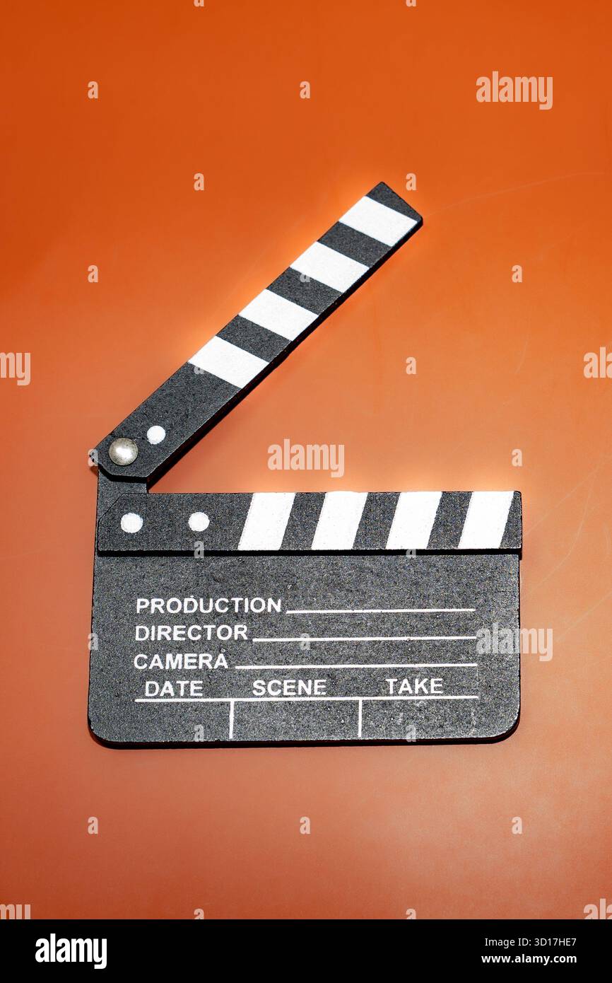 Un claquette de film classique est ouvert, prêt pour le tournage, sur un fond orange vif. Banque D'Images