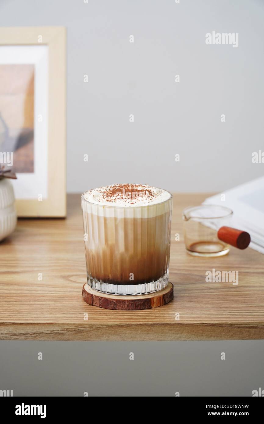 Café glacé avec mousse crème. Café glacé avec de la mousse de crème dans une tasse en verre sur une table en bois, concept de boisson matinale confortable Banque D'Images