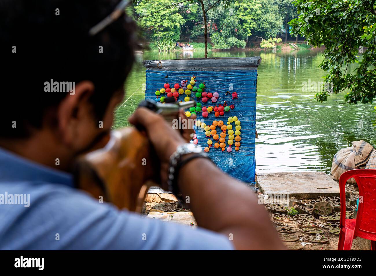Homme tirant sur des cibles de montgolfières pendant une activité de plein air au bord du lac Banque D'Images