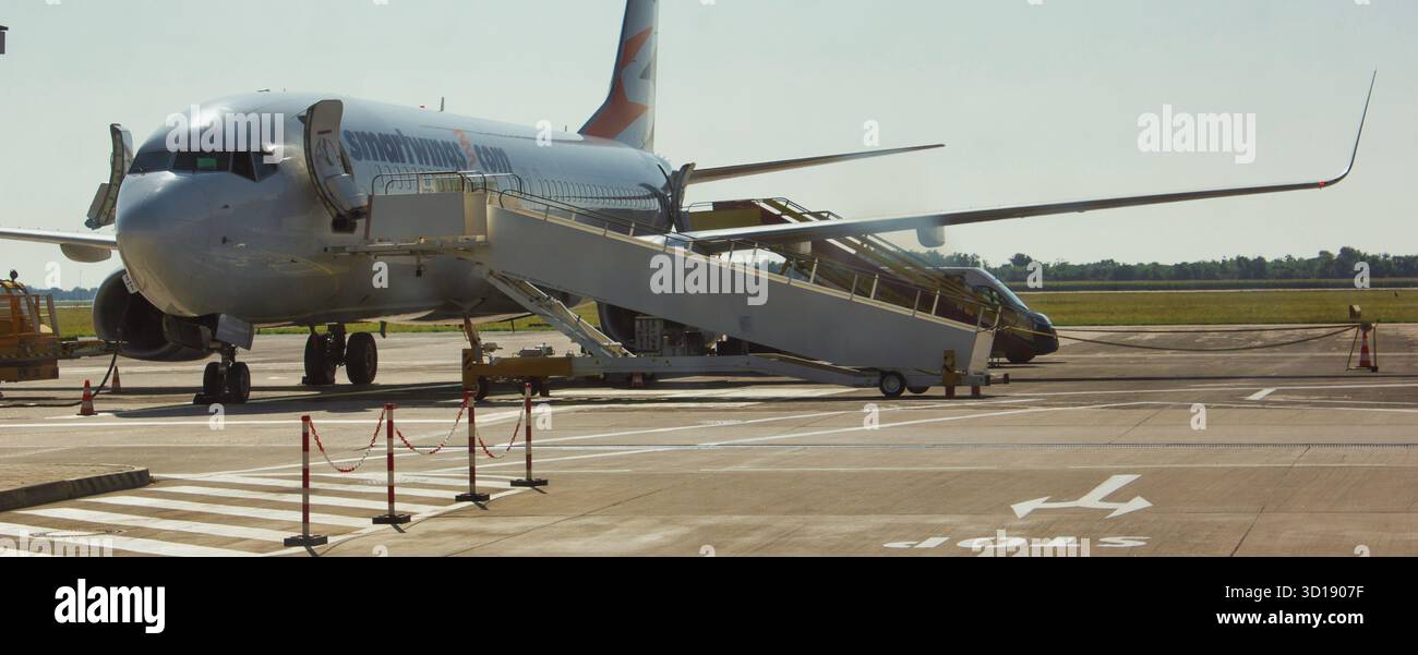 Cette image représente un avion commercial stationné sur l'aire de trafic d'un aéroport. Les escaliers d'embarquement de l'avion sont prolongés, attendant les passagers Banque D'Images