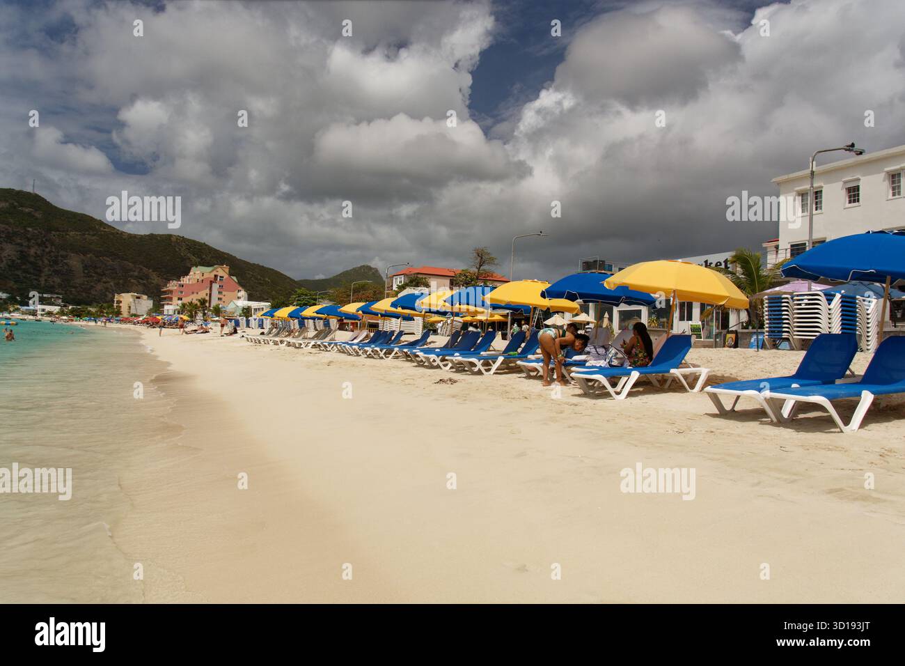St Maarten - les amateurs de plage apprécient le soleil avec des fauteuils inclinables et des parasols colorés. Banque D'Images
