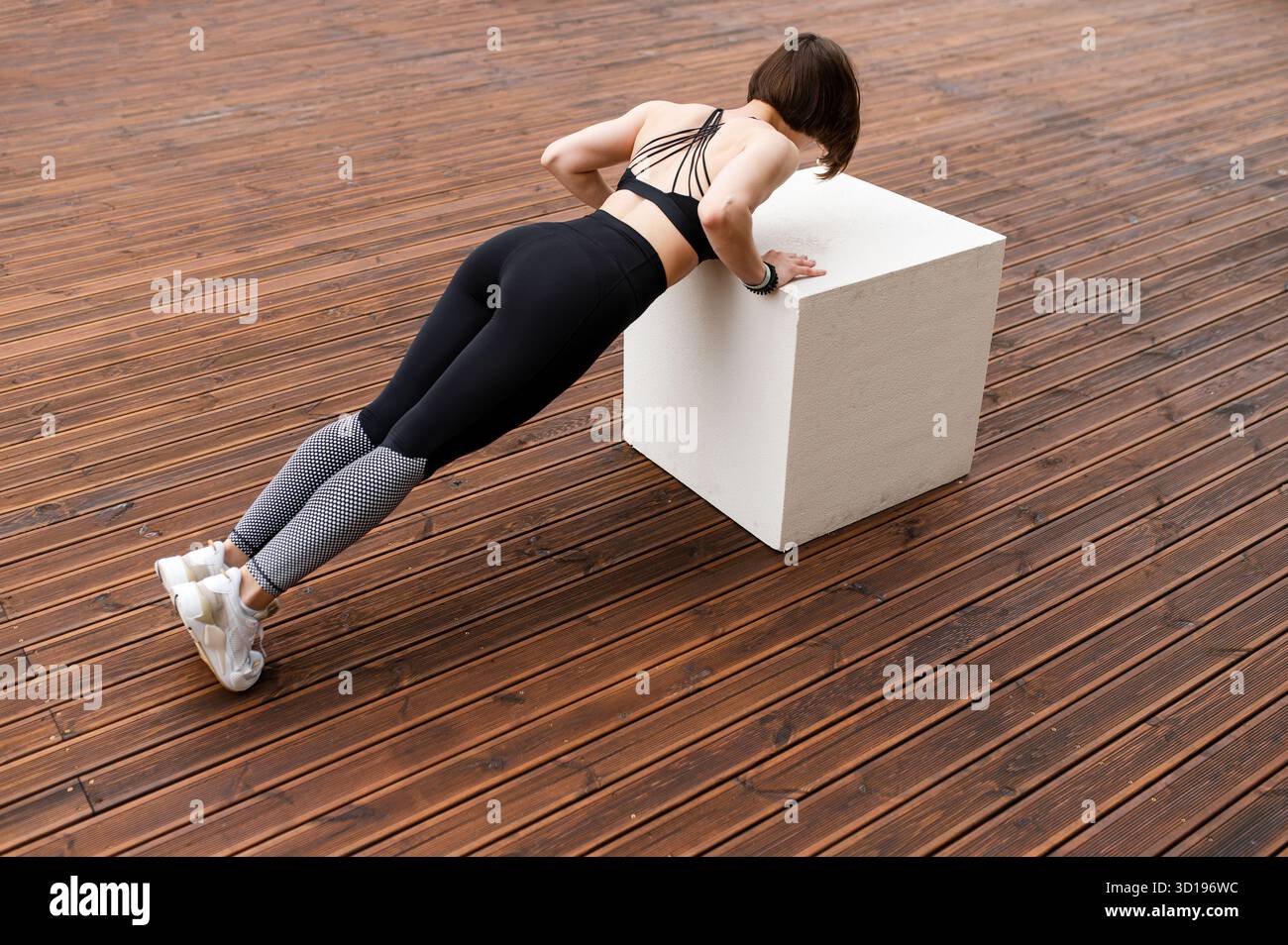 Sportive faisant des pompes sur cube sur la zone en bois Banque D'Images