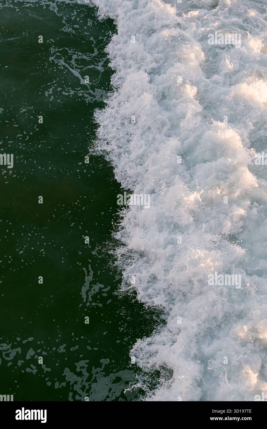 Gros plan vertical des vagues océaniques avec réflexion du soleil Banque D'Images