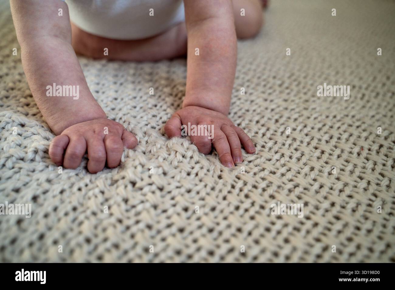 Gros plan des mains d'enfant sur la couverture neutre pour bébé Banque D'Images