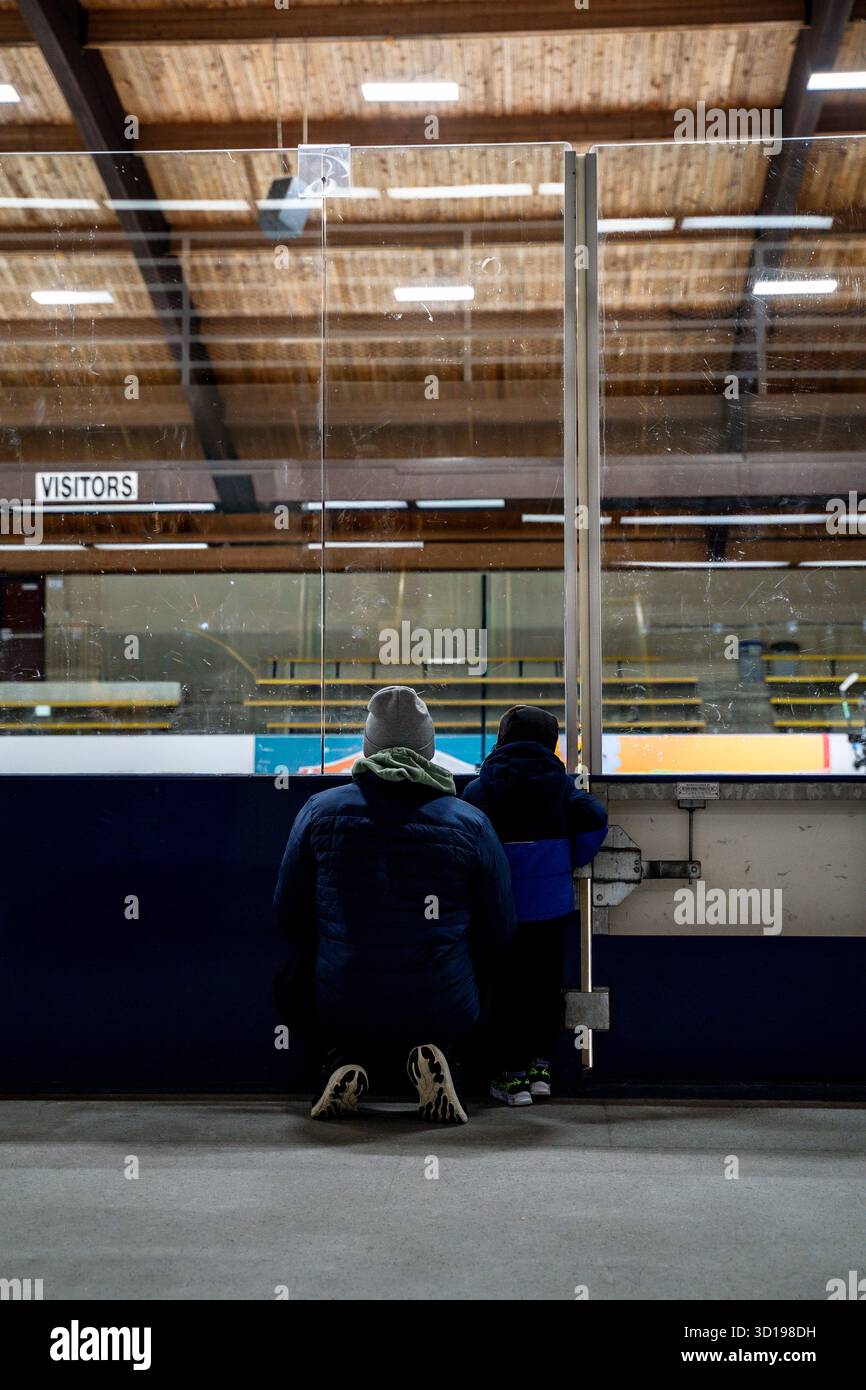 Enfant garçon et papa admirant les patineurs ensemble sur la patinoire intérieure Banque D'Images