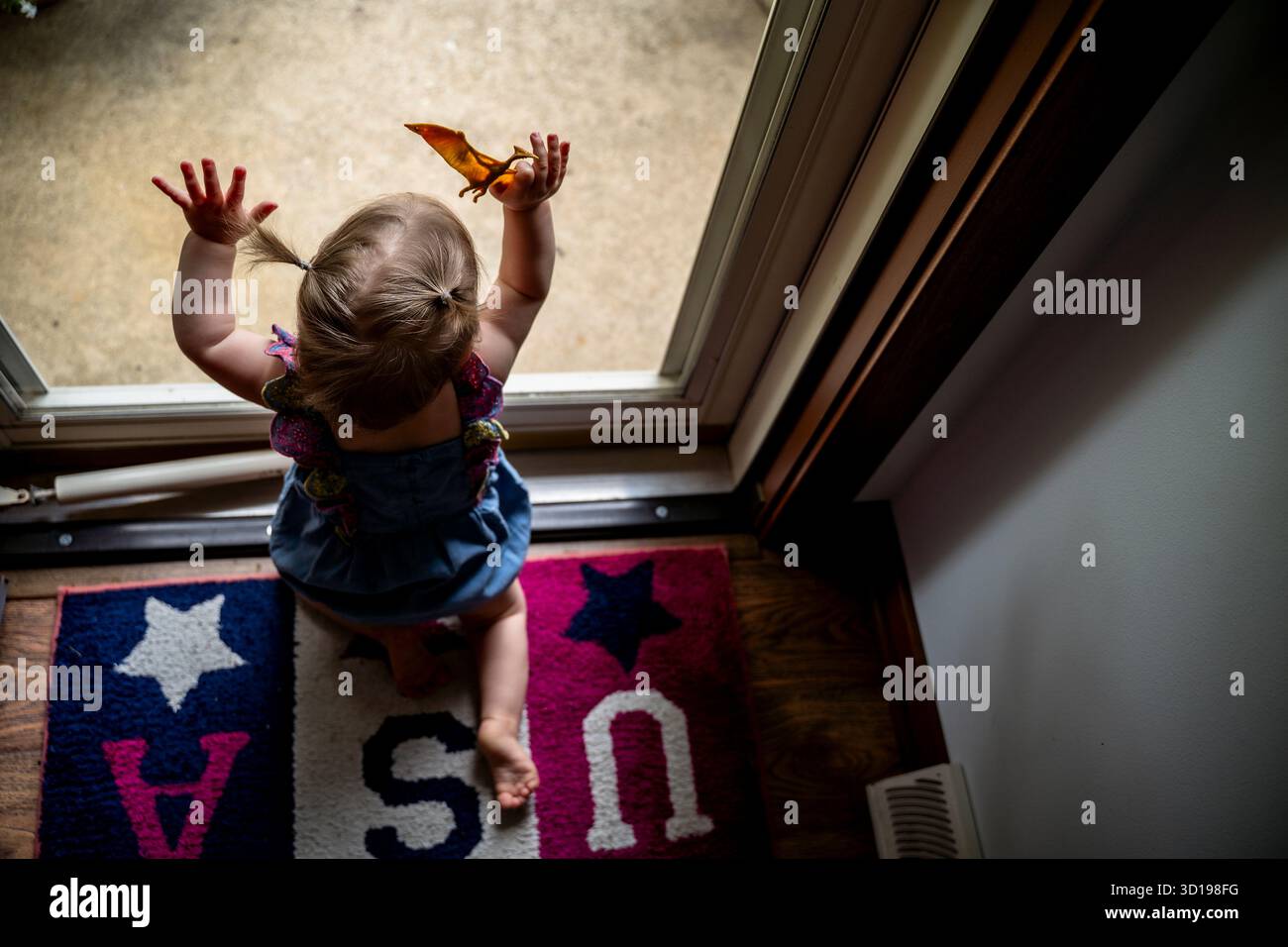 Vue aérienne de la petite fille regardant par la porte d'entrée avec jouet Banque D'Images
